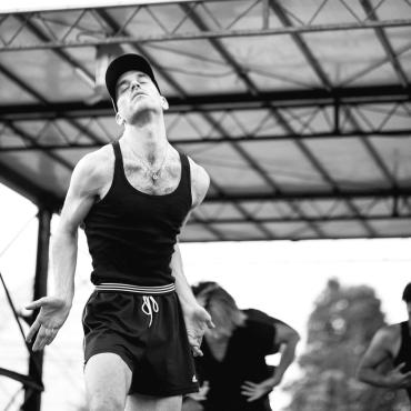 Scott Stafford, a dancer in a black tank top and shorts, engaged in movement.