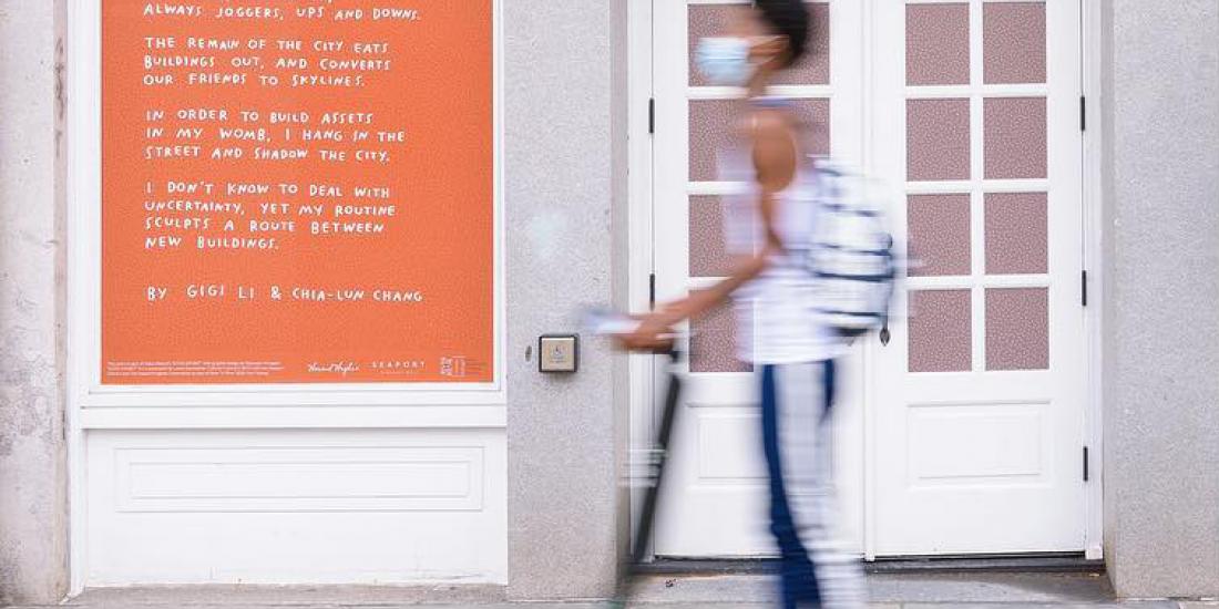 Poetry written to the side of a door, with a scooter rider passing by.