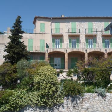 Photo of the Panorama building with foliage and a rock wall in front.