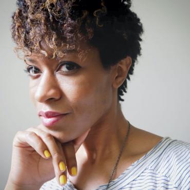 Black woman with short curly hair looking toward the camera