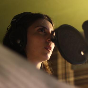 Amanda Ekery singing into a microphone, holding sheet music