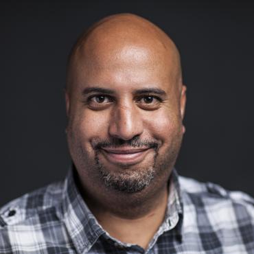 Michael against a black background looking at the camera and smiling.