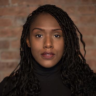 Portrait of Alicia Waller standing against a brick background