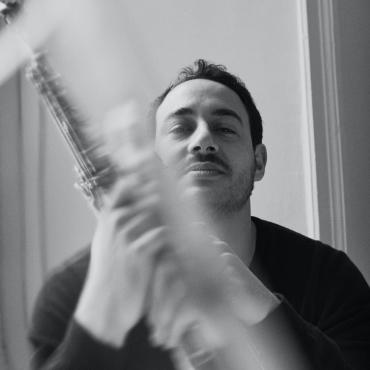 Yacine Boulares holding a blurred soprano saxophone