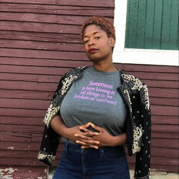 A thirty-nine year old Black Woman writer with a cute outfit is looking off into the distance.