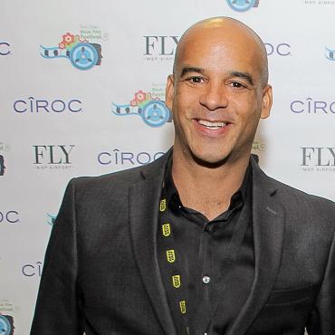 Film premiere event photo of James smiling in front of a step and repeat backdrop at film festival.