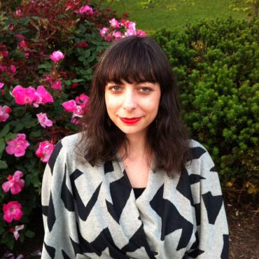 Melissa Levin, smiling at the camera standing in front of a hedge.