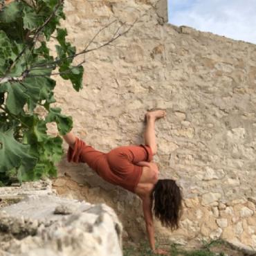 A dancer moving upside down along a sea wall.