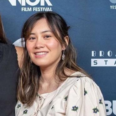 Marcie LaCete, a twenty-something mixed Caucasian and Asian woman, wearing a cream floral blouse, smiling at the camera at the Bushwick Film Festival.