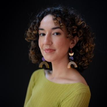 A twenty-something Latina woman smiling at the camera.