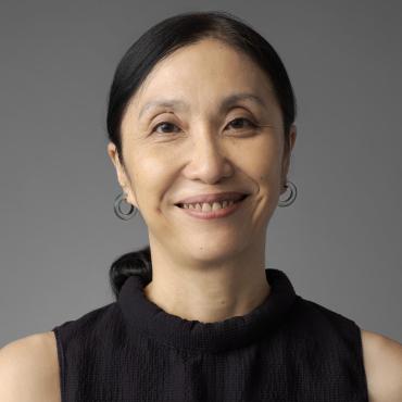 Janet smiling at the camera against a gray background