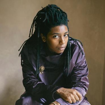 Safiyah Chiniere, a 33-year-old Black woman with locs looking into the camera.