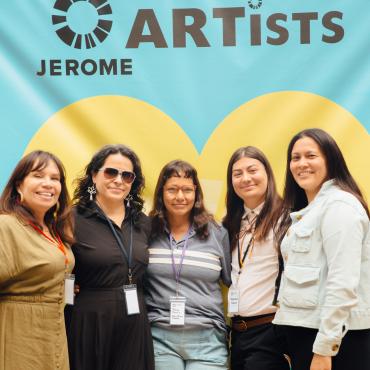 A group smiling at the camera against a heart backdrop.