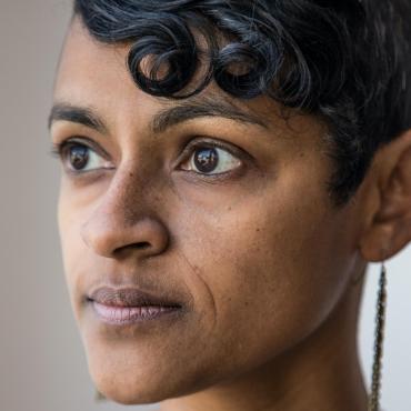 Headshot in profile of a middle aged woman,South Asian American artist with short, curly hair